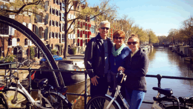 A family with bicycles on a bridge over a canal having an Amsterdam bike tours experience