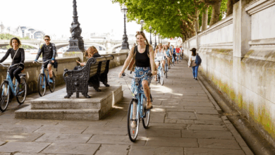 A group riding bikes along the banks of the Thames River on a London Bike Tour