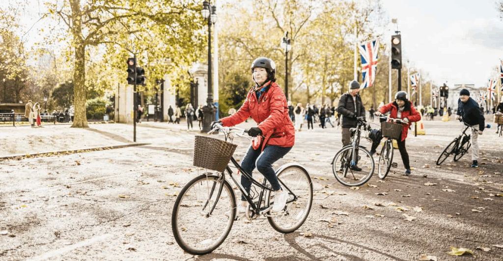 A group of older riders on a cycling tour in a tree lined London street enjoying the best London tours