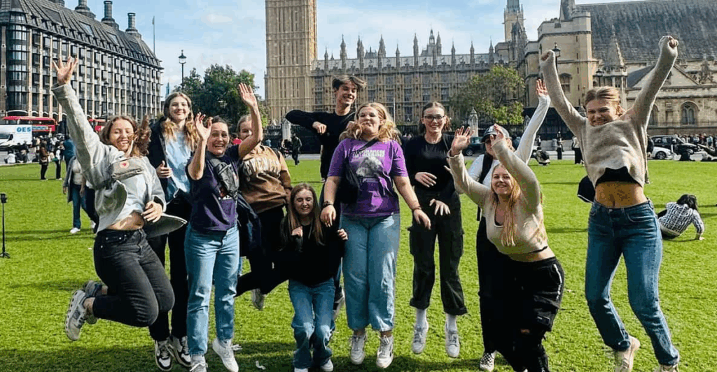A group of younger students all jumping for joy in a field in central London while enjoying the best London tours