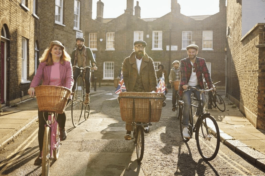 A small group of cyclists on bikes with huge baskets and one on a penny farthing bicycle with an eccentric looking tour guide enjoying the best London tours
