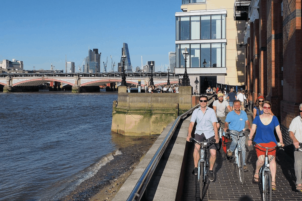 A group adults on bicycles having a good along the banks of the Thames on a London Bike Tour