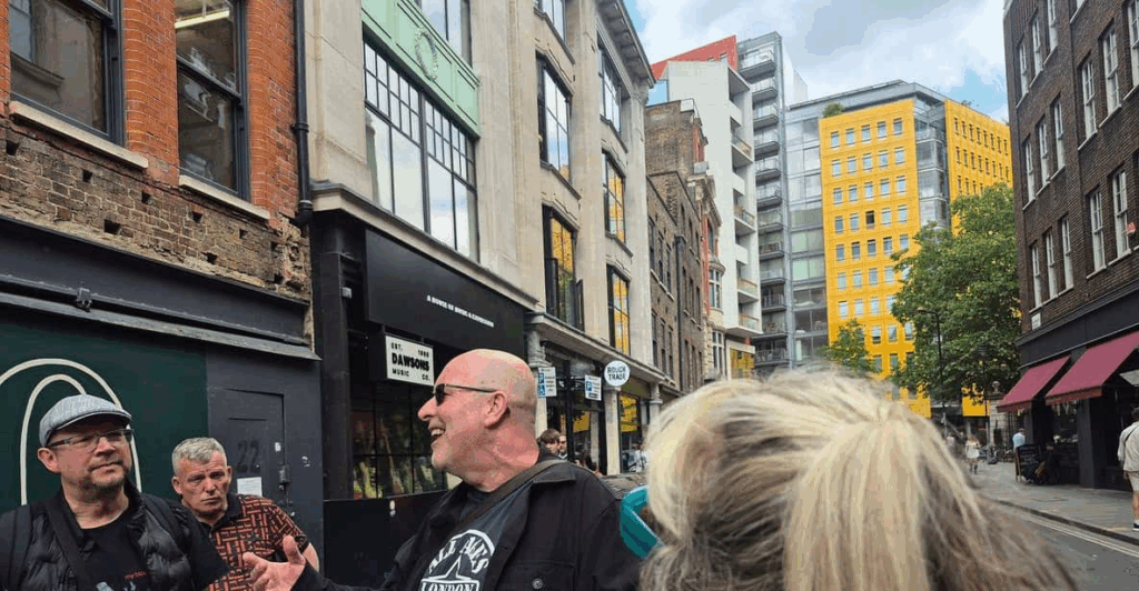 A side alley in London with a group tour and tour guide looking like a rocker from the 1970’s on a London Bike Tour