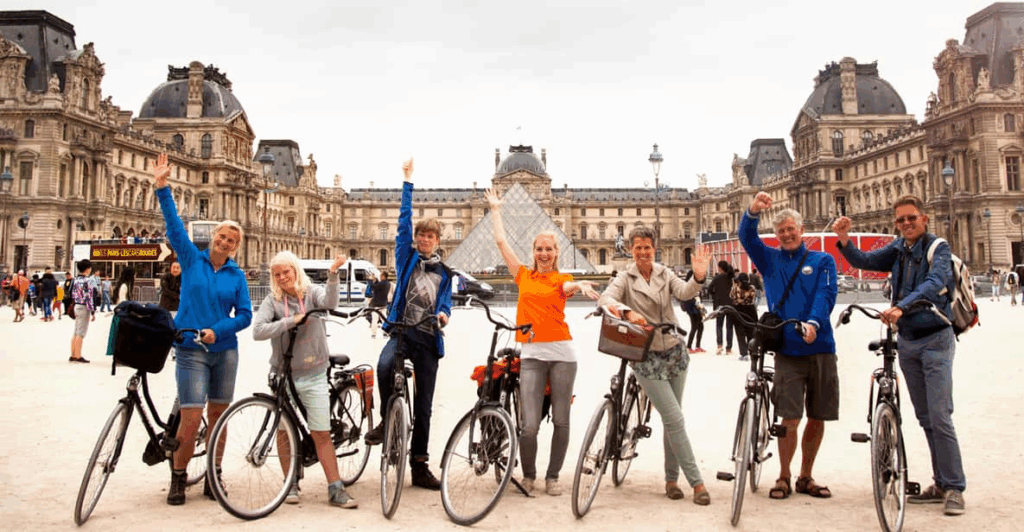 A group of cyclists with the Louvre in the background on a Paris Bike Tour