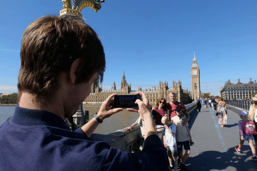 A tour guide taking pictures of a family on a bridge over the Thames River on a London private tours activity