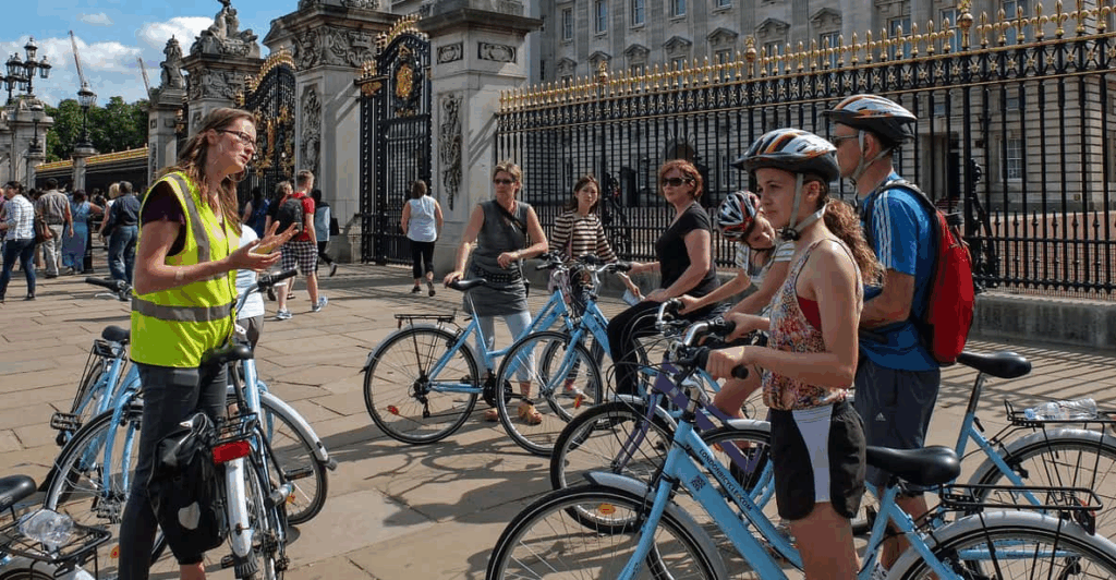 A tour guide talking to family groups on bikes in front of Buckingham Palace on a London private tours activity