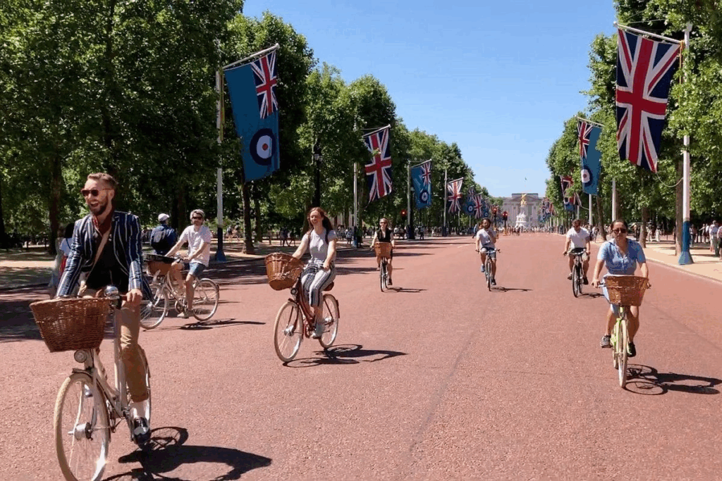 A group of people on bikes riding along a flag lined street on a London private tours activity