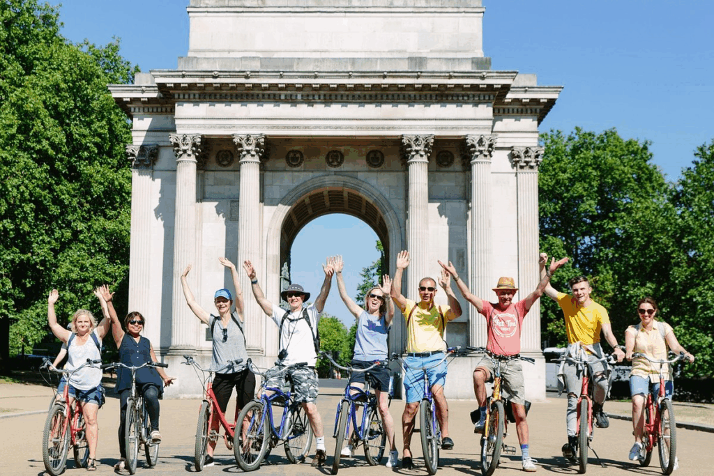 A group of happy bike riders on a cycling tour with their hands in the air enjoying the best London tours