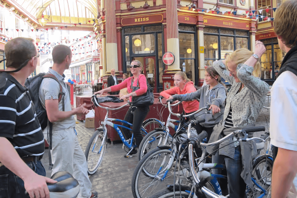 London bike tour guide briefing cyclists and families with bikes inside historic Leadenhall Market during a city cycling tour.