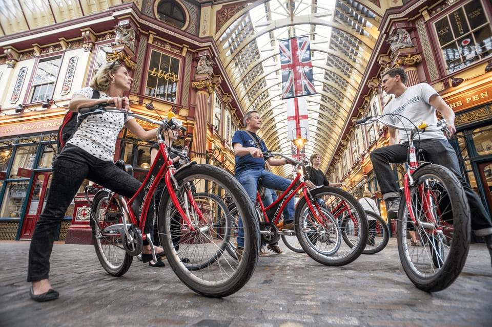 London bike tour guide stopping with cyclists inside the historic Leadenhall Market during a guided city bike tour.
