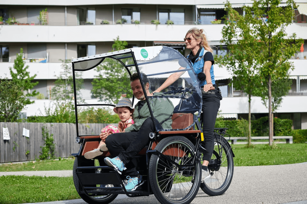 Parents and child riding a covered family cargo bike, highlighting practical family transport choices for munich bike rental visitors.